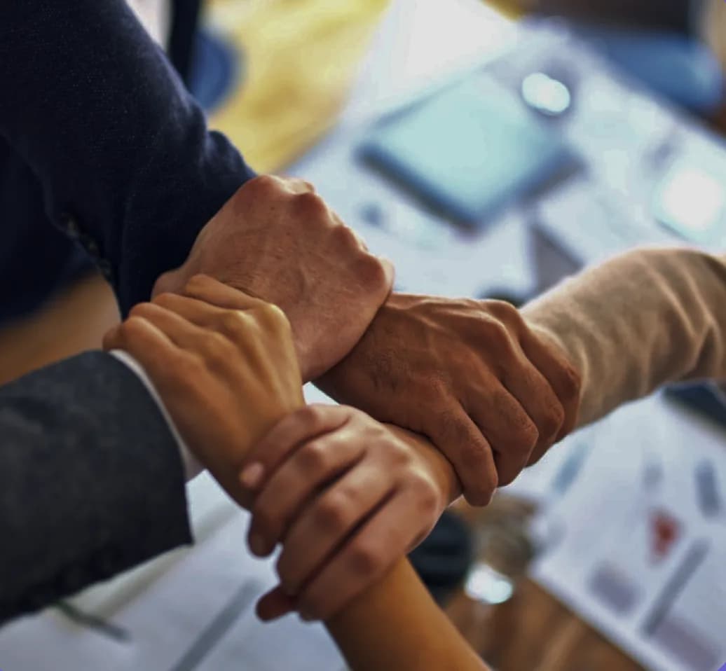 The EduCuby team joining hands around a work table